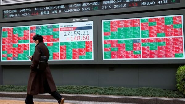 A man walks past an electronic board showing Japan's Nikkei average and stock prices outside a brokerage