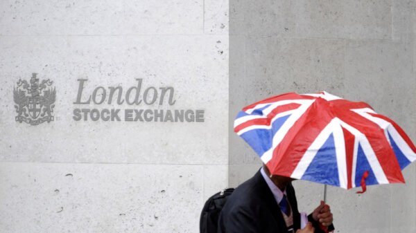 FILE PHOTO: A worker shelters from the rain under a Union Flag umbrella as he passes the London Stock Exchange in London, Britain, October 1, 2008. REUTERS/Toby Melville