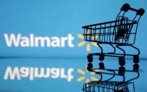 Shopping trolley is seen in front of Walmart logo in this illustration