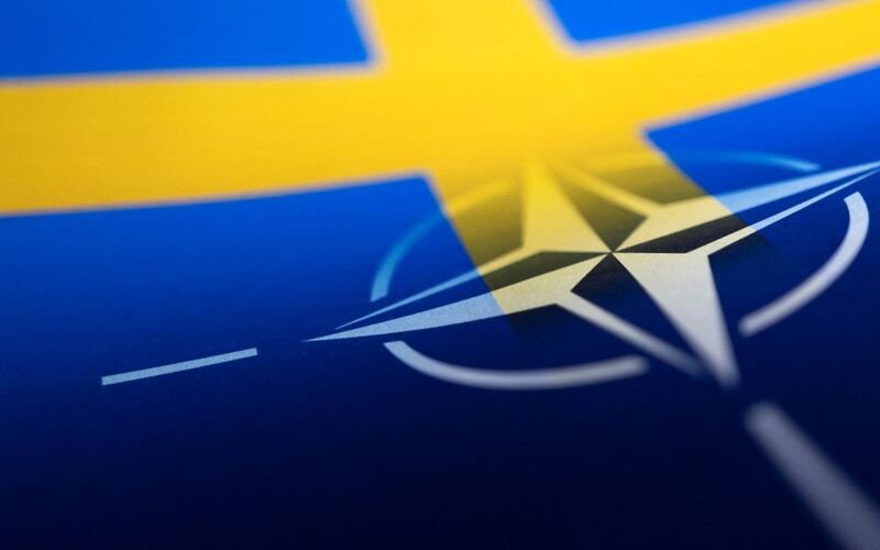 Swedish and NATO flags are seen printed on paper this illustration