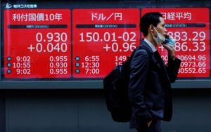 A man walks past an electronic board displaying Japan's 10-year government bonds level, the current Japanese Yen exchange rate against the U.S. dollar and Nikkei share average, outside a brokerage in Tokyo, Japan, October 31, 2023. REUTERS/Kim Kyung-Hoon