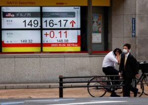 Passersby walk past an electric monitor displaying the Japanese yen exchange rate against the U.S. dollar outside a brokerage in Tokyo, Japan October 4, 2023. REUTERS/Issei Kato/file photo