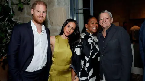Getty Images for Netflix Harry and Meghan smiling next to two others, wearing cocktail attire, at a house