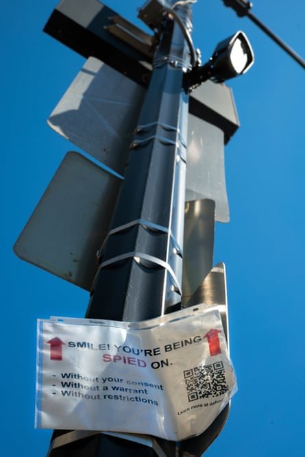 a sign affixed to a pole reads ‘smile you’re being spied on’